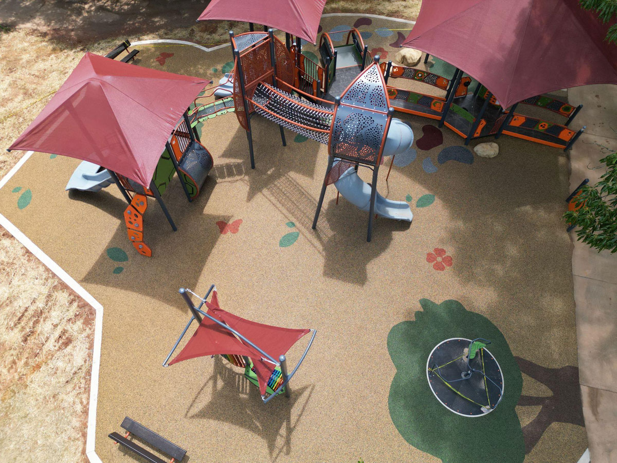 Colorful playground with shaded structures, slides, and textured flooring