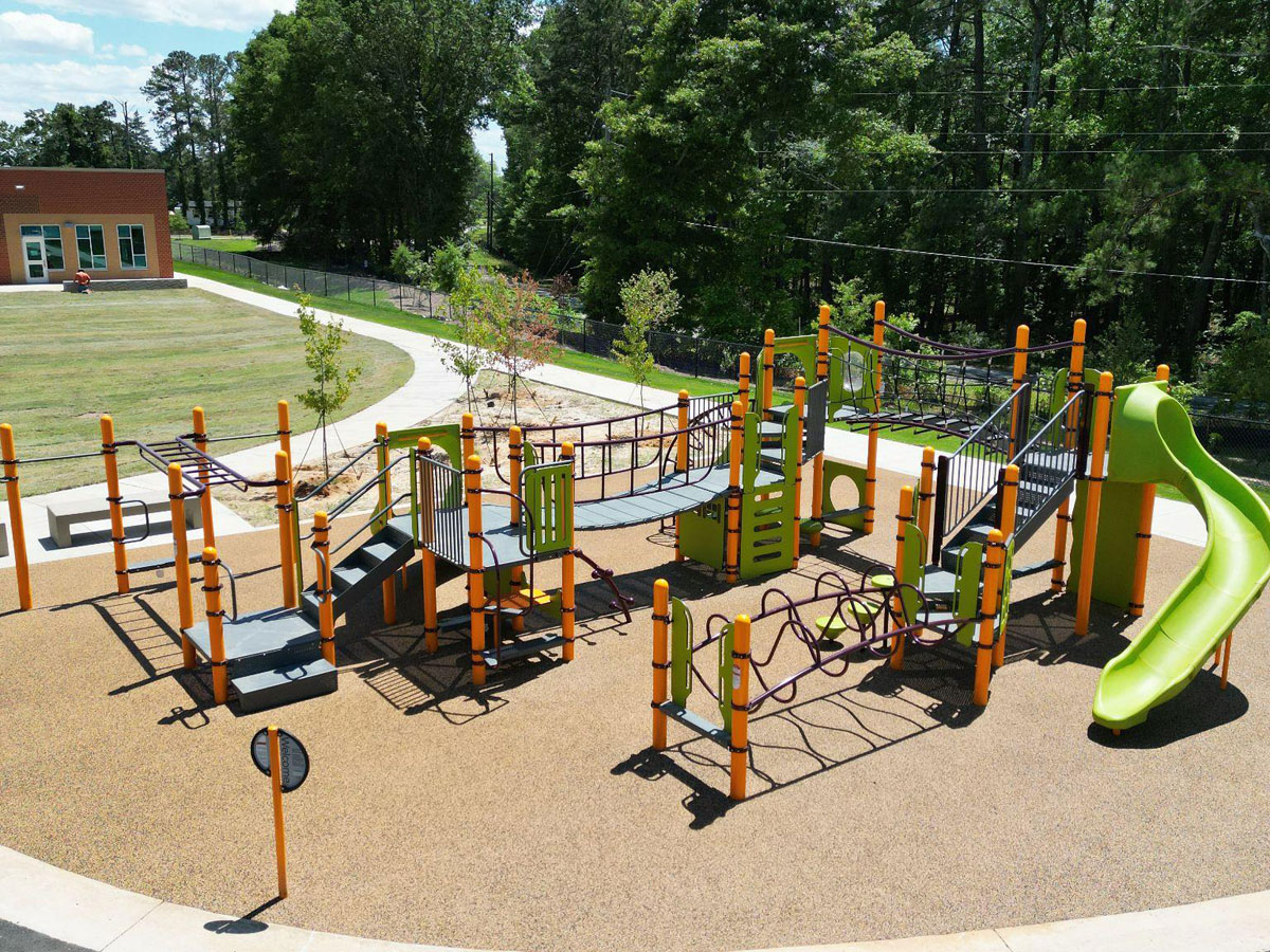 Tan rubber flooring beneath colorful playground equipment with slides and climbing structures