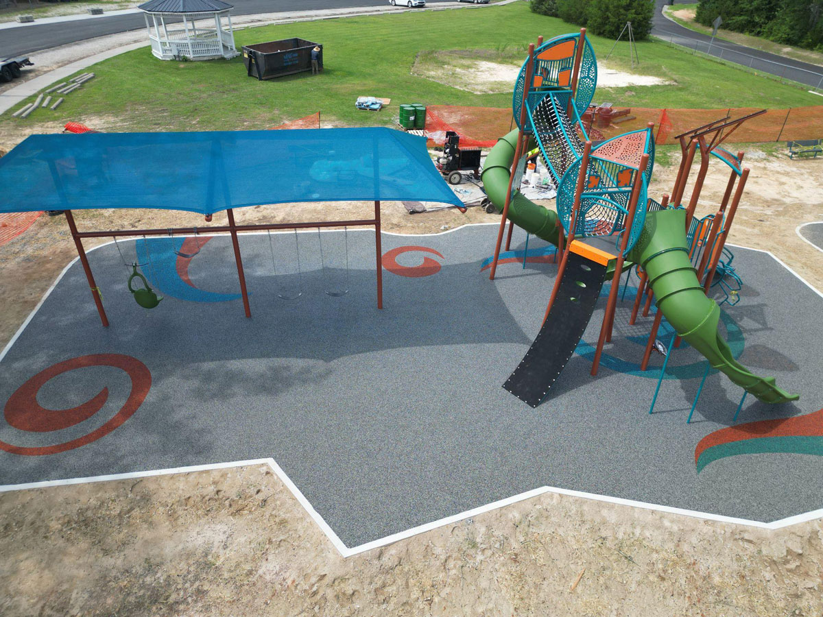 Colorful rubber flooring with swirling patterns under a playground with swings and slides