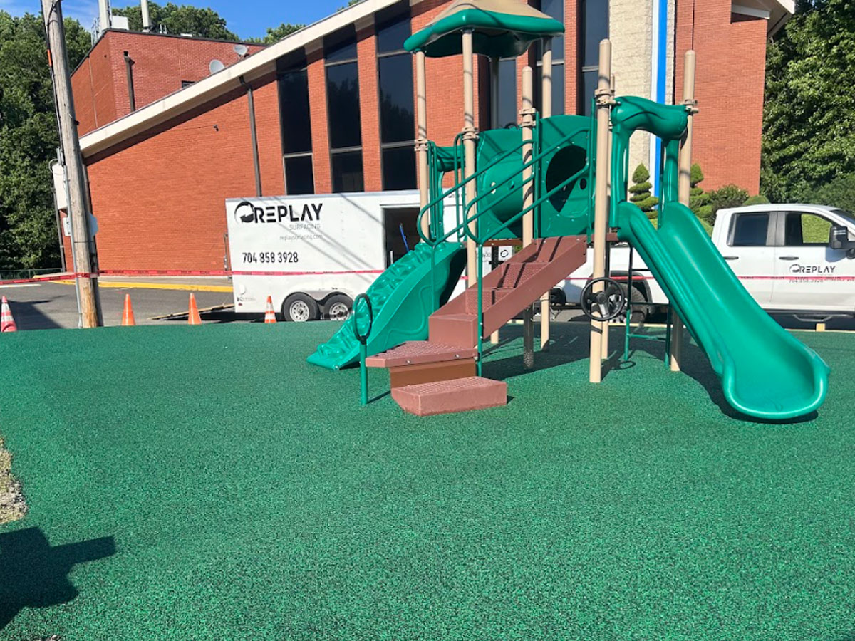 Green rubber flooring under a playground with a slide and stairs