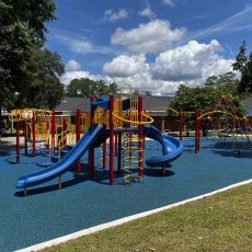 A vibrant kids playground featuring swings and a slide installed over poured in place rubber surfacing, providing a safe, durable, and shock-absorbing outdoor rubber surface ideal for playground safety and comfor